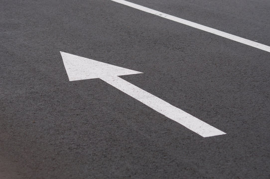 Arrow on asphalt, driving direction on asphalt road. Concept movement, life, business, direction of movement