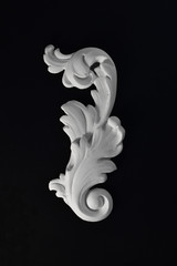 White stucco acanthus leaf on a black background.