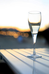 Calice singolo con dentro un aperitivo alcolico sopra un tavolo su sfondo tramonto