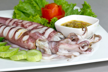 Grilled squid and spicy seafood sauce  with vegetables on white plate, Thai food.