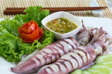 Grilled squid and spicy seafood sauce  with vegetables on white plate, Thai food.