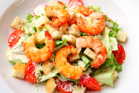 The best fresh salad of prawns in the white dish. Caesar salad with fried shrimps, tomatoes, cheese, lettuce. Healthy food concept. - Stock image