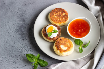 Cottage cheese pancakes or fritters with jam, natural yogurt or sour cream and mint. Traditional Ukrainian and Russian cuisine. Syrniki. Healthy and diet breakfast.