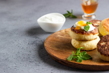 Cottage cheese pancakes or curd fritters decorated honey, sour cream and mint. Healthy and diet breakfast.