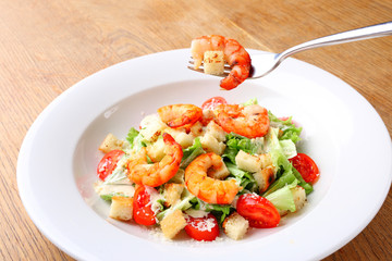 The best fresh salad of prawns in the white dish. Caesar salad with fried shrimps, tomatoes, cheese, lettuce. Healthy food concept. - Stock image