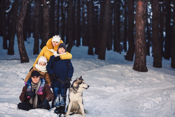 Fototapeta na wymiar Happy european young family with big dog posing against winter pine forest