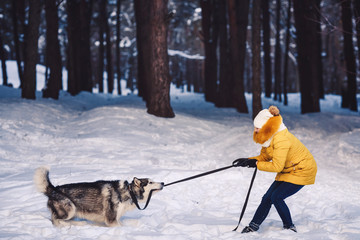 Beautiful young girl funny playing with her dog in winter in park