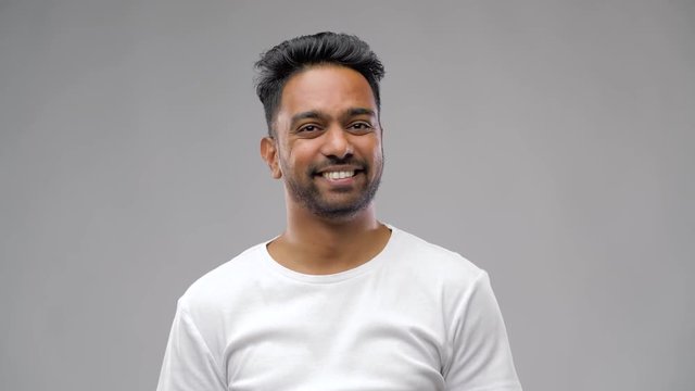 people, emotion and expression concept - confused indian man shrugging shoulders over grey background
