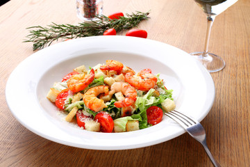 The best fresh salad of prawns in the white dish. Caesar salad with fried shrimps, tomatoes, cheese, lettuce. Healthy food concept. - Stock image