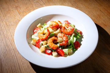 The best fresh salad of prawns in the white dish. Caesar salad with fried shrimps, tomatoes, cheese, lettuce. Healthy food concept. - Stock image
