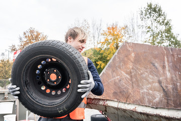 Mann entsorgt Altreifen in Container von Recyclingzentrum 