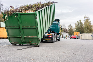 LKW lädt Container mit Grünschnitt auf dem Wertstoffhof auf 