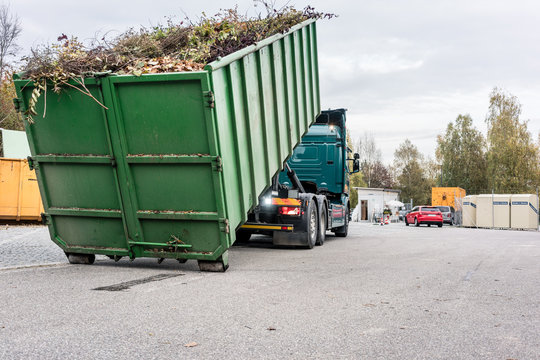 LKW l&auml;dt Container mit Gr&uuml;nschnitt auf dem Wertstoffhof auf 