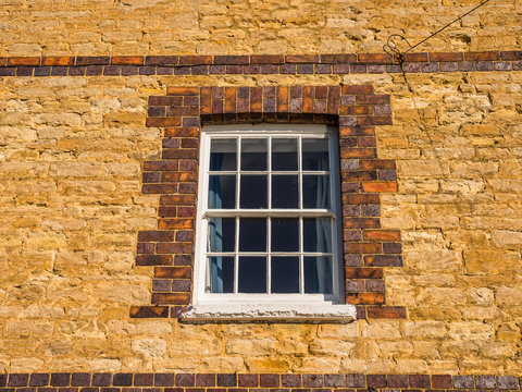 sunny day view of old white window on old brick wall in england