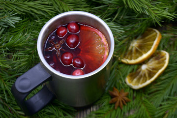Christmas mulled wine with cranberries in metal mug Winter warming drink with spices decorated with fir branches dried oranges