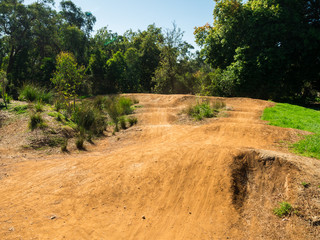 Jumps and obstacles on a BMX bike race track in a suburban park.