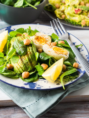 Avocado spinach salad with chickpeas and hard boiled eggs served on a dish. Fats and proteins