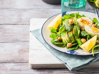 Avocado spinach salad with chickpeas and hard boiled eggs served on a dish. Fats and proteins