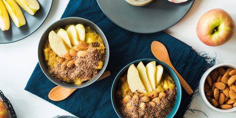 Cozy morning concept with turmeric amaranth porridge served with apples, flax seeds and almonds....