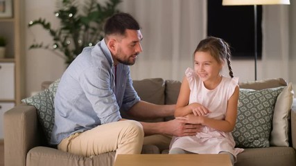 family, childhood and fatherhood concept - happy father and little daughter tickling and having fun on sofa at home