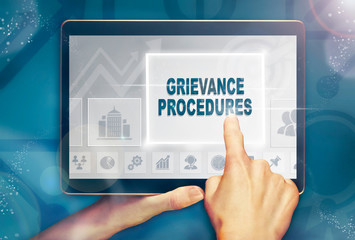 A hand selecting a Grievance Procedures business concept on a computer tablet screen with a colorful background.