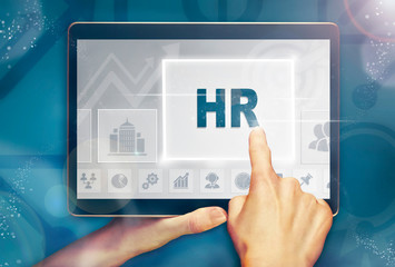 A hand selecting a HR business concept on a computer tablet screen with a colorful background.
