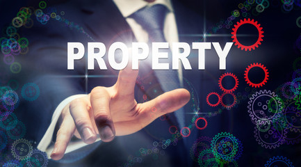 A businessman pressing a Property business concept on a graphical display of cogs