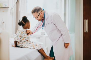 Physician listening to the heart beat of a little girl