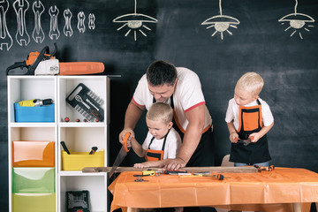 Father and two sons working in the carpentry workshop.	