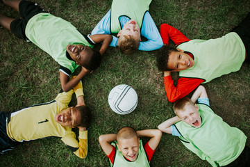 Junior football team lying around a football