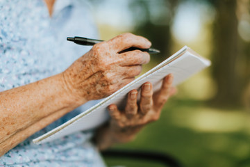 Senior woman writing down her memories into a notebook