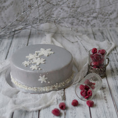 Obraz na płótnie Canvas French raspberries mousse cake with New Years decoration - snowflakes and white branches - on a white wooden background. New Year's or Christmas cake. Scandinavian style. Copy space, selective focus