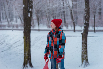 Joyful child girl is going to roll down the hill in the winter Park.