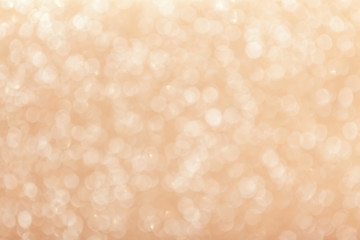 Blurred shiny beige background with sparkling lights.