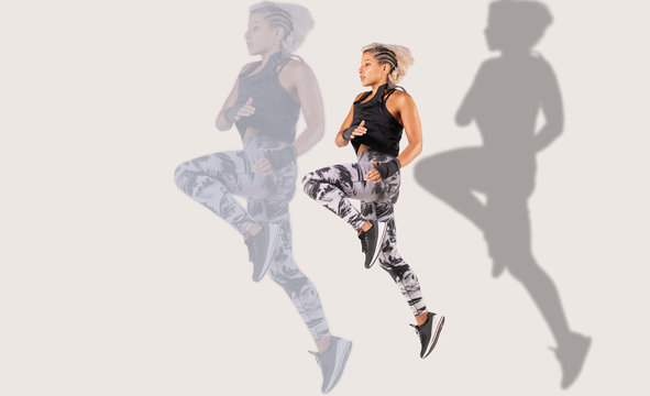 Composite of .a beautiful female Middle Eastern fitness athlete  with  modern funky hairstyle and wearing sports clothing doing a dramatic leap with a shadow and larger reflection on background  