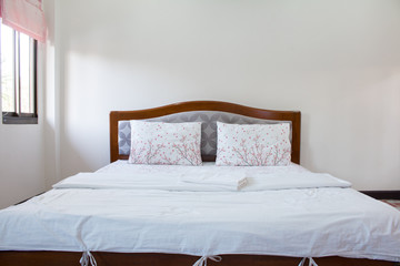 Close up white pillow and bedding sheets on natural white wall bedroom background, Messy bed concept