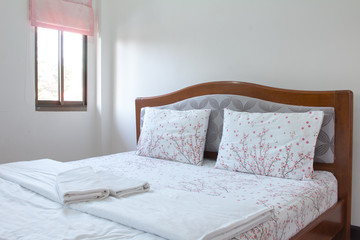 Close up white pillow and bedding sheets on natural white wall bedroom background, Messy bed concept