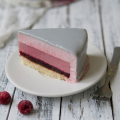 French raspberries mousse cake with New Years decoration - snowflakes and white branches, on a white wooden background. Christmas cake. Slice of cake. Scandinavian style. Copy space, selective focus