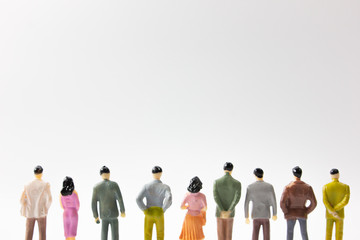 A group of miniature business people stand on white background back view cut legs.