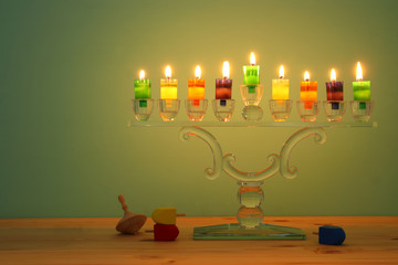 image of jewish holiday Hanukkah background with crystal menorah (traditional candelabra) and colorful oil candles