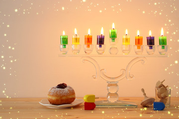 image of jewish holiday Hanukkah background with crystal menorah (traditional candelabra) and colorful oil candles.
