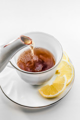 Cup of tea with lemon. Pour tea from teapot into cup.