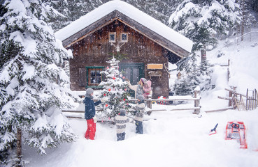 Austria, Altenmarkt-Zauchensee, family decorating Christmas tree at wooden house