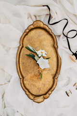 Wedding fashion details. Creative floristry. Groom's boutonniere. golden tray background. textile background, and ribbon Top view, top view, flat composition.