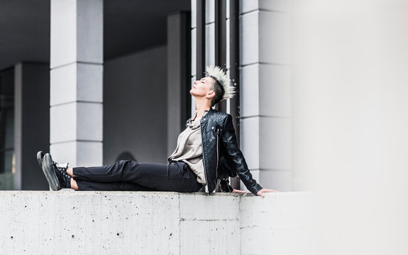 Punk Woman Sitting On A Wall With Closed Eyes