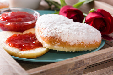 Valentine's Day breakfast with coffee, heart-shaped bun, berry jam and roses on a tray. Close up