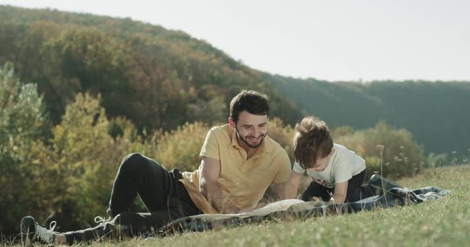 Beautiful sunny day that with his small boy laying down on the garage and playing together at nature.