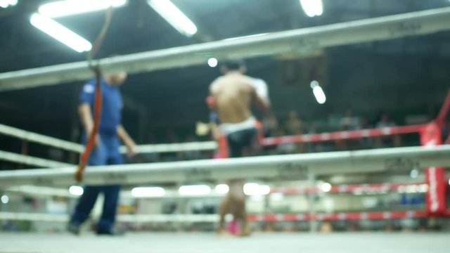 asian men thai boxing are punch and kick to the leg then foeman fall down knockout on floor  with committee on canvas boxing stadium