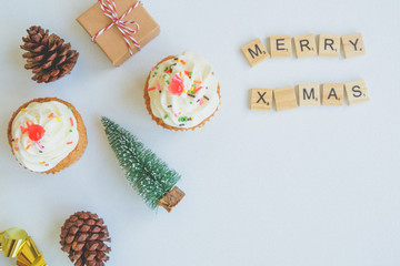 Christmas background, decorated with cupcake, pinecone, Christmas tree and paper box present over the white background