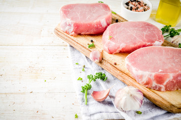 Cooking meat dinner background. Raw fresh meat, pork brisket boneless steak, with spices, herbs, olive oil, top view